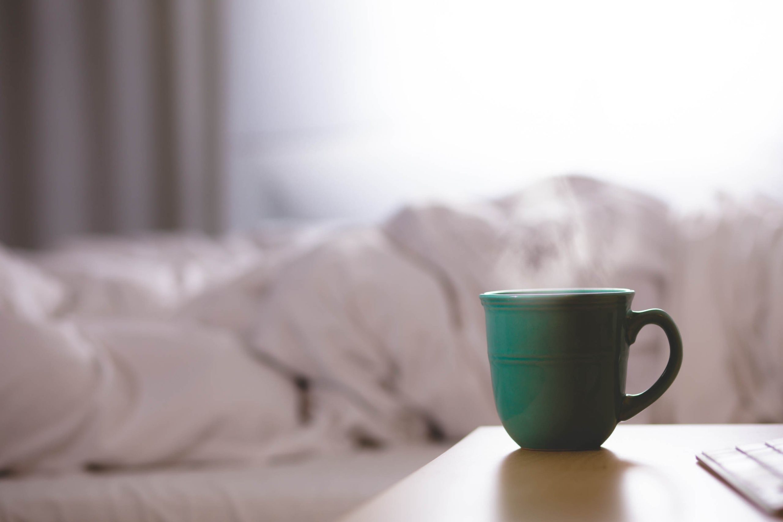 coffee-cup-on-table-with-bed-in-background coffee-cup-on-table-with-bed-in-background